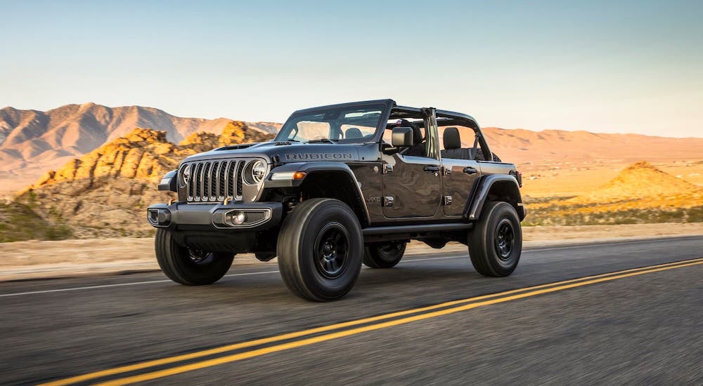 A gray 2021 Jeep Wrangler Unlimited Rubicon 392 with no roof is driving on a desert highway.