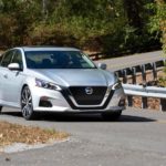 A silver 2021 Nissan Altima is driving on a winding road.