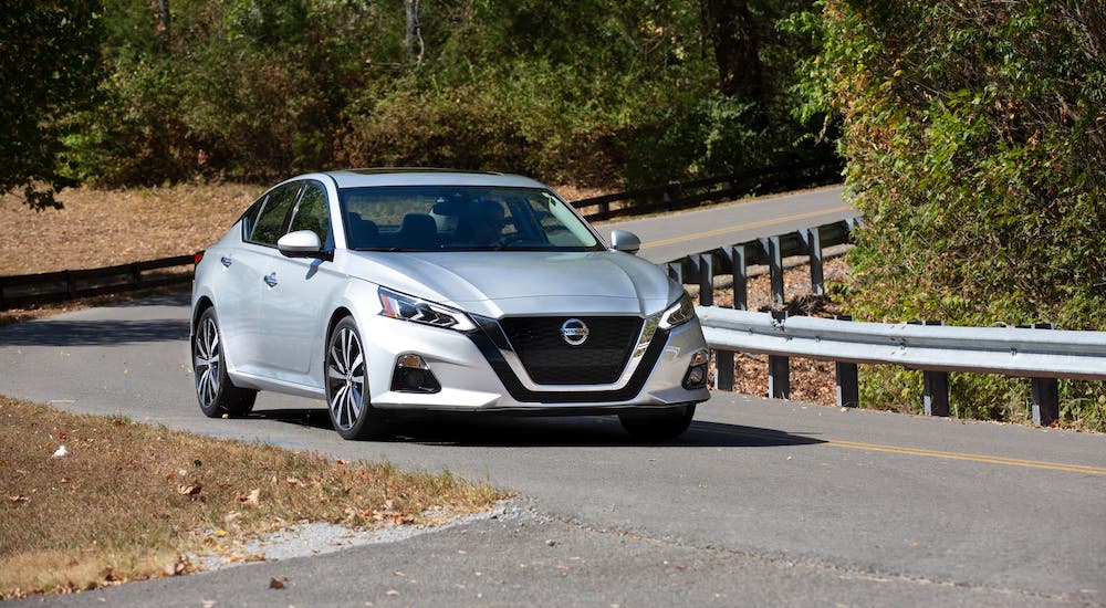 A silver 2021 Nissan Altima is driving on a winding road.