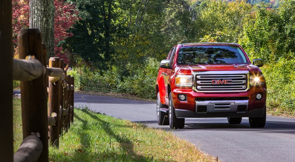 A red 2018 GMC Canyon SLT Diesel is driving past a fence after leaving a used GMC dealer.