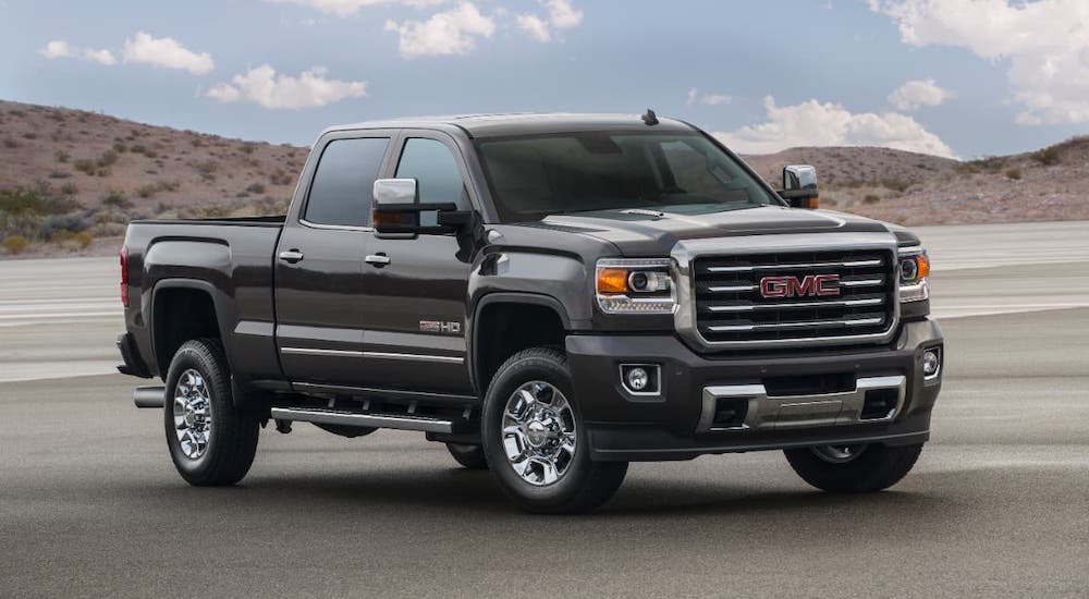 A black 2016 GMC Sierra 2500HD is parked in front of distant hills.