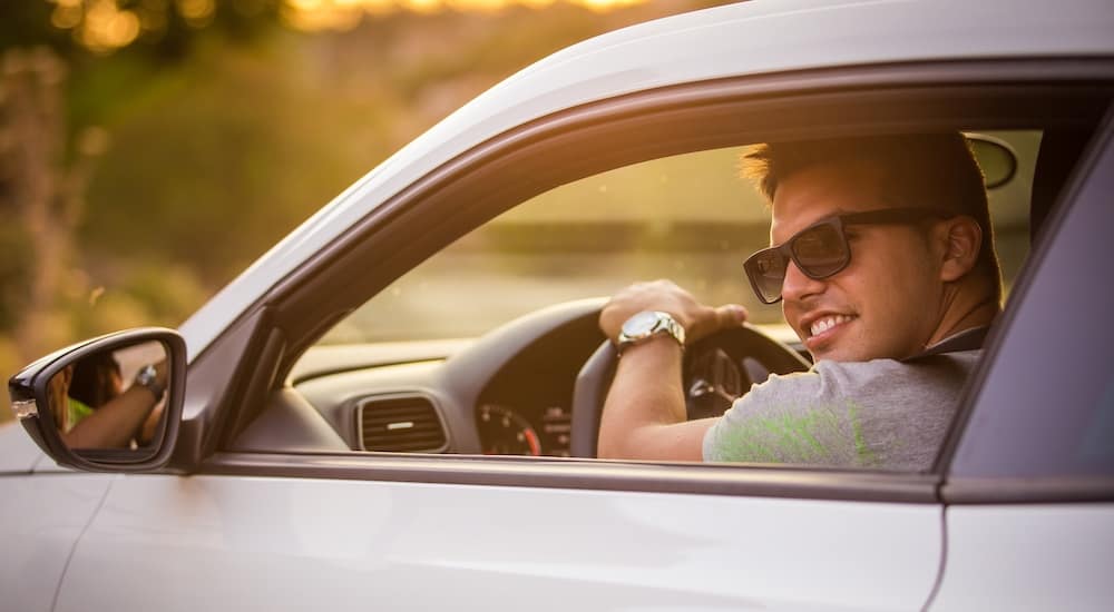 A teen driver is shown driving a white car through the window.