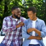 A father is passing his son a set of keys as he gives teen driver advice.