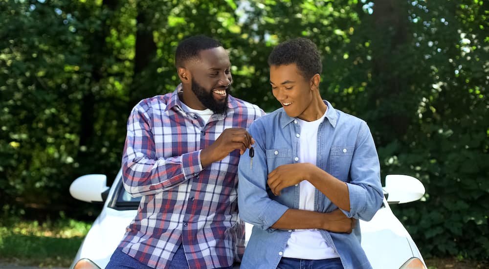 A father is passing his son a set of keys as he gives teen driver advice.