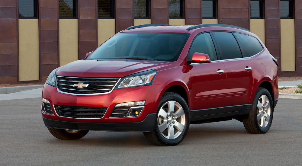 A red 2014 Chevy Traverse is shown from an angle parked in a paved lot after leaving a used Chevrolet dealer.