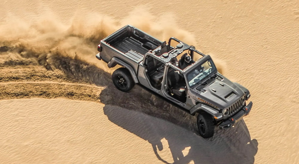 A grey 2021 Jeep Gladiator is shown from above driving in a desert after leaving a used Jeep dealer.