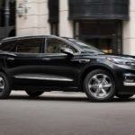 A black 2021 Buick Enclave is driving through a city after winning a 2021 Buick Enclave vs 2022 Nissan Pathfinder comparison.