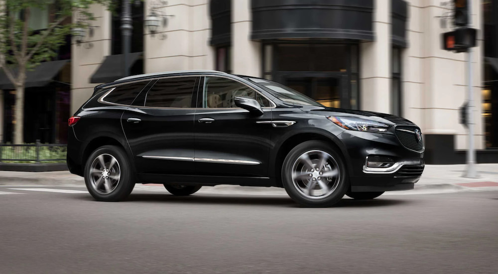 A black 2021 Buick Enclave is driving through a city after winning a 2021 Buick Enclave vs 2022 Nissan Pathfinder comparison.