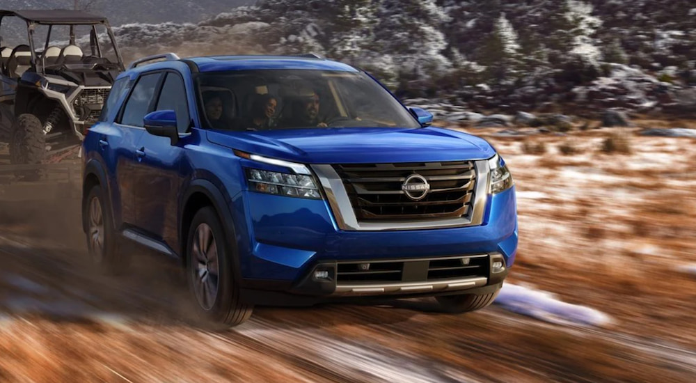 A blue 2022 Nissan Pathfinder is driving through the mountains. 