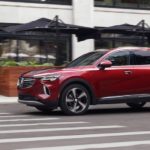 a red 2021 Buick Envision is driving through a city.
