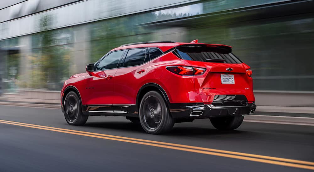 A red 2021 Chevy Blazer is shown from an angle driving past a building.