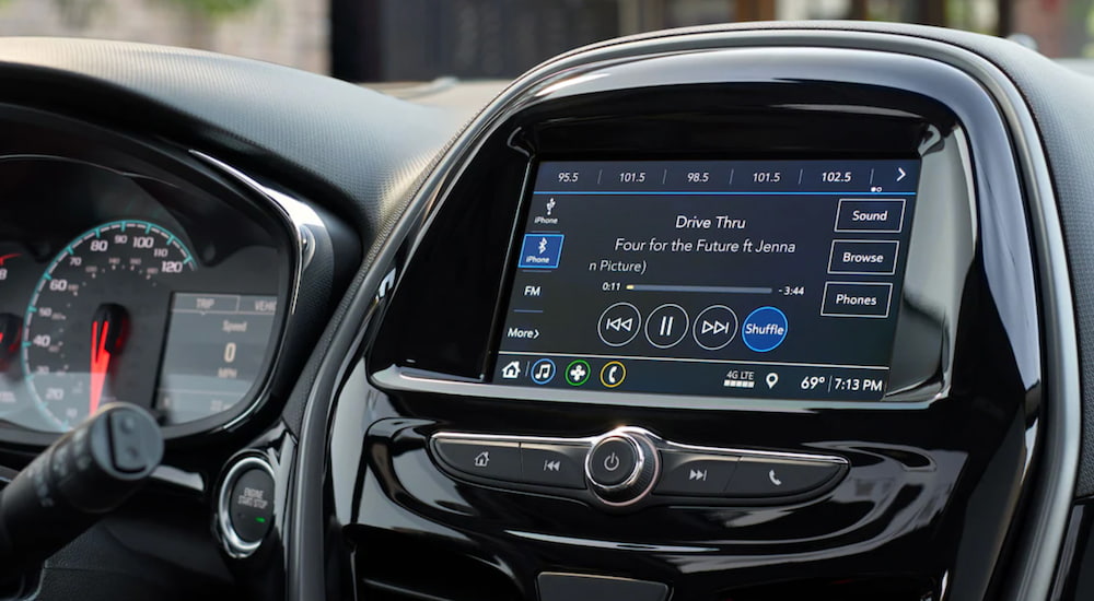 The interior of a 2021 Chevy Spark shows "Drive Thru" playing on the infotainment screen. 