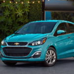 A Turquoise 2021 Chevy Spark is parked in a driveway after winning a 2021 Chevy Spark vs 2021 Mitsubishi Mirage comparison.