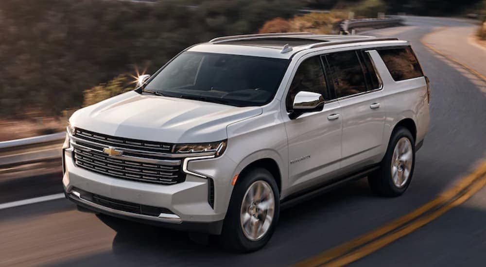 A silver 2021 Chevy Suburban is driving down a two lane road.