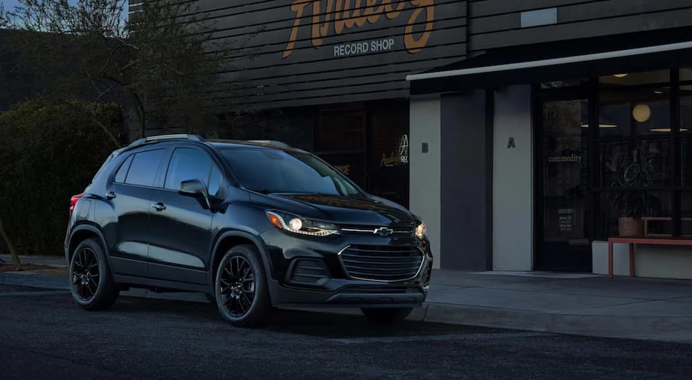 A black 2021 Chevy Trax is parked in front of a record store at dusk.