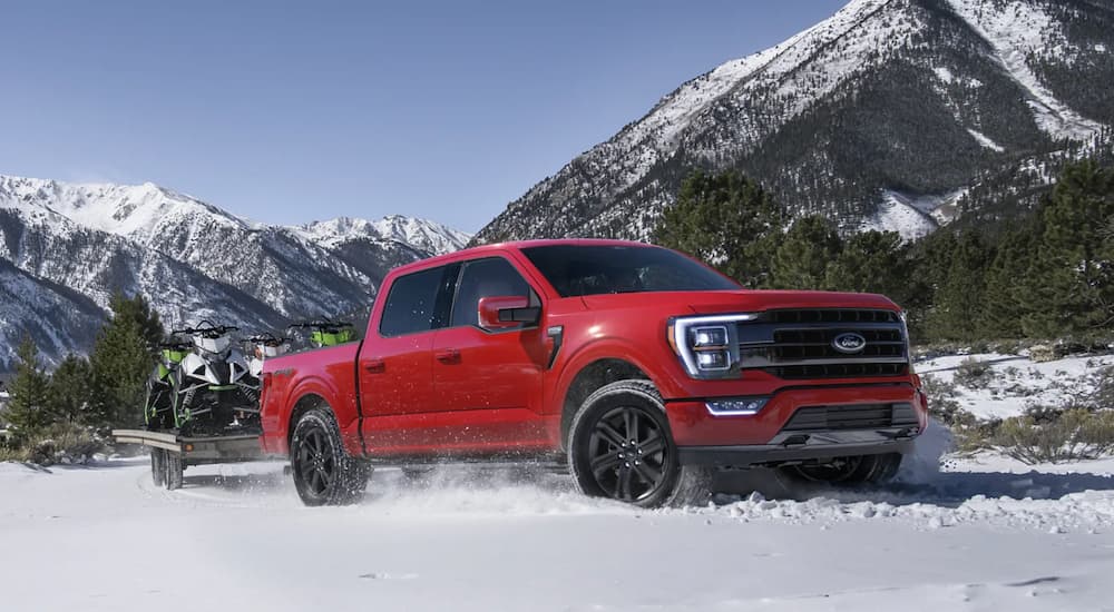 A red 2021 Ford F-150 is driving through the snow after winning a 2021 Ford F-150 vs 2021 Nissan Titan comparison.