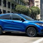 A blue 2021 Honda HR-V Sport is driving through a city.