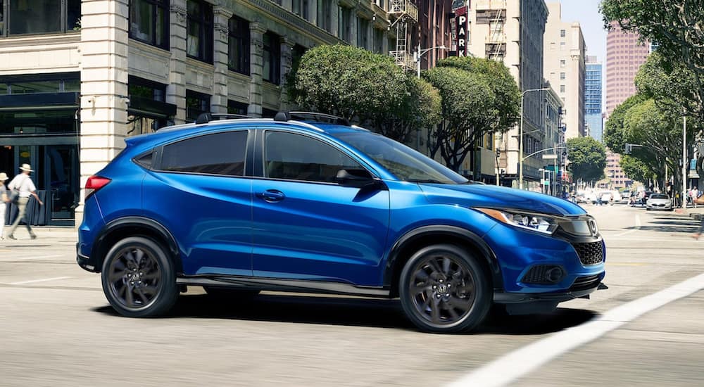 A blue 2021 Honda HR-V Sport is driving through a city.