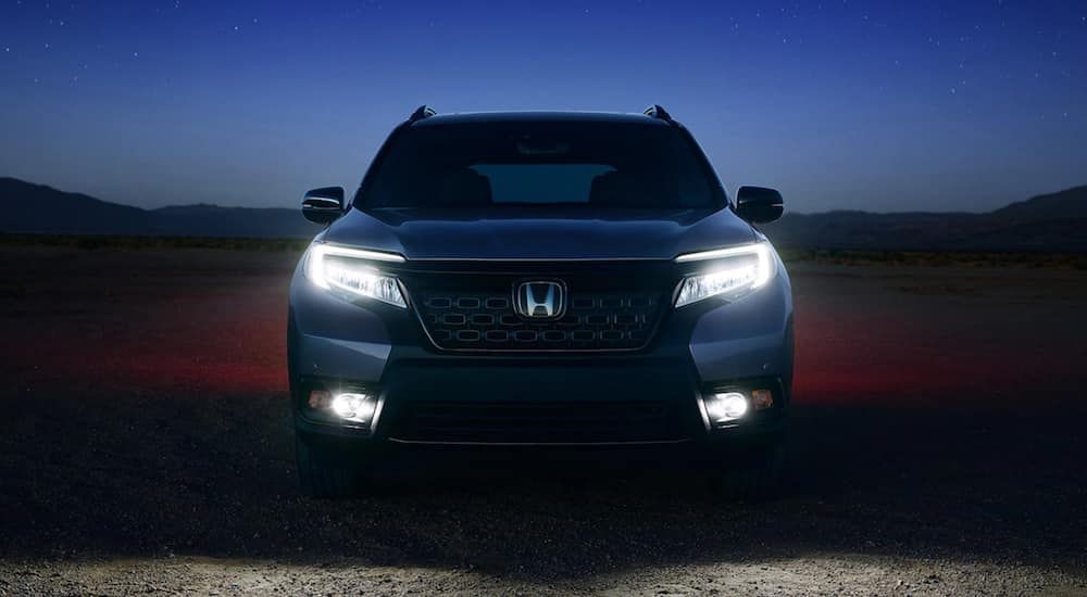 The front of a 2021 Honda Passport is shown with it's lights on in the dark.