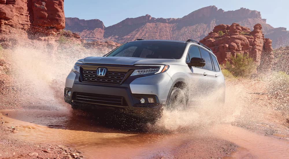 A silver 2021 Honda Passport is shown driving through a puddle in the desert.