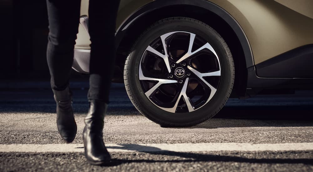 A 2021 Toyota C-HR shows a close up of a rear wheel and woman walking on the street.