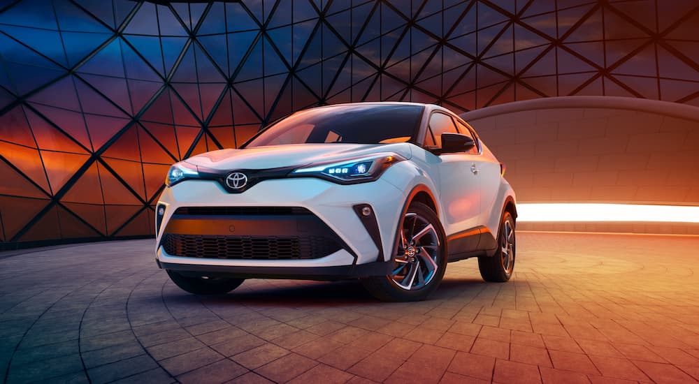 A white 2021 Toyota C-HR is parked in a modern gallery with orange led lights.