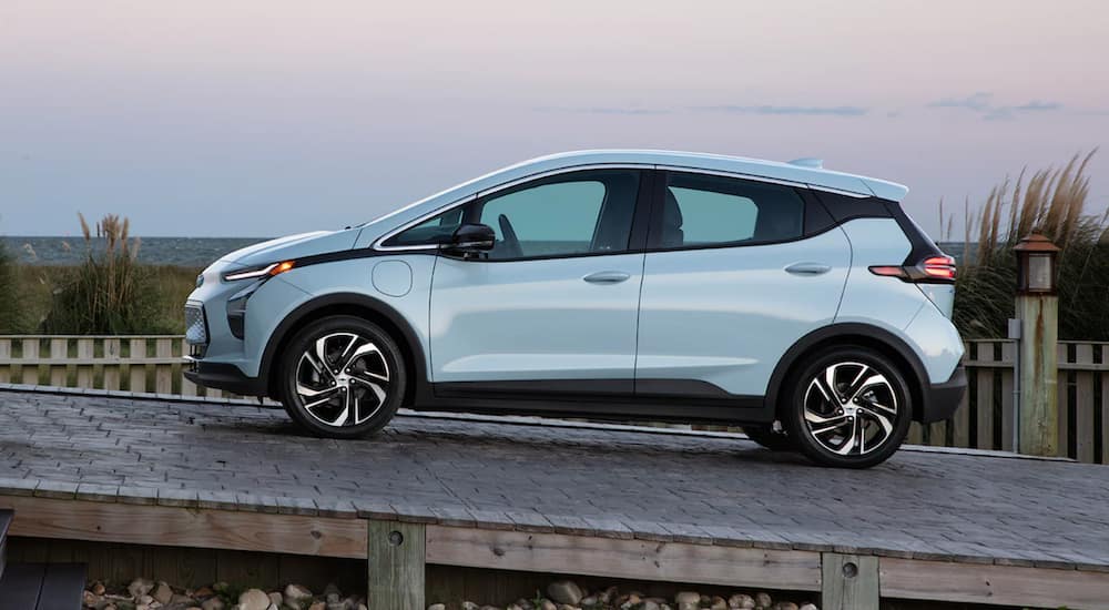 A light blue 2022 Chevy Bolt EV is driving up a ramp at sunset.