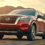 A red 2022 Nissan Pathfinder is shown from the front parked at the base of a mountain.