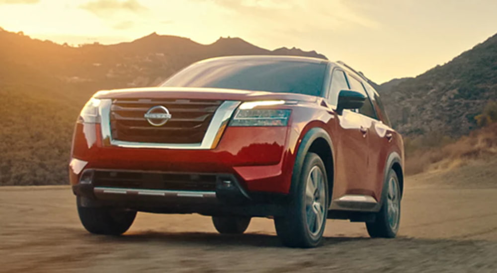 A red 2022 Nissan Pathfinder is shown from the front parked at the base of a mountain.