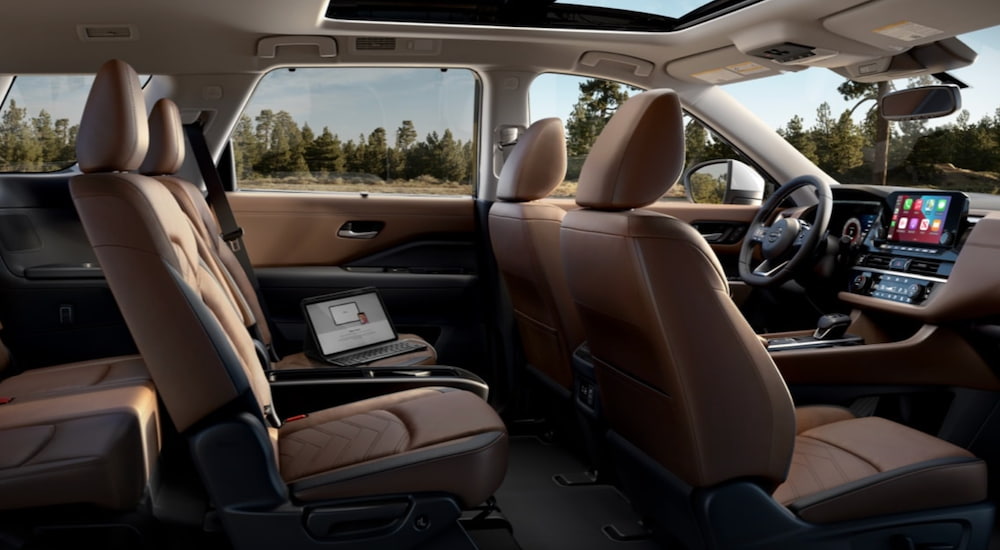 The interior of a 2022 Nissan Pathfinder shows three rows of seating, the steering wheel and infotainment screen.