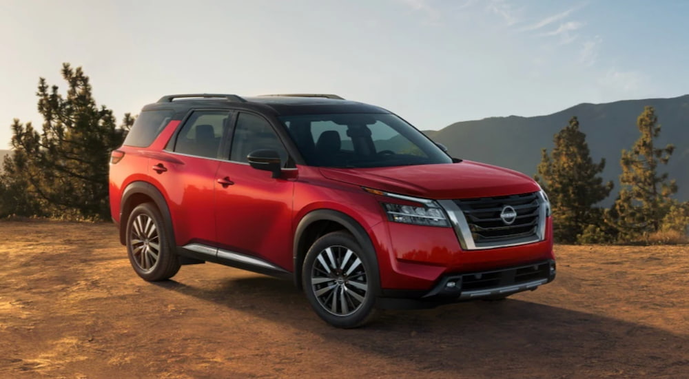 A red 2022 Nissan Pathfinder is shown angled to the right parked on dirt.