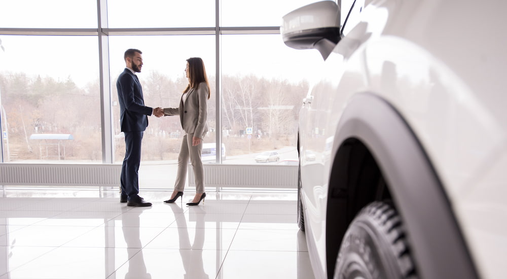 A man and woman shake hands at a buy here, pay here dealership.