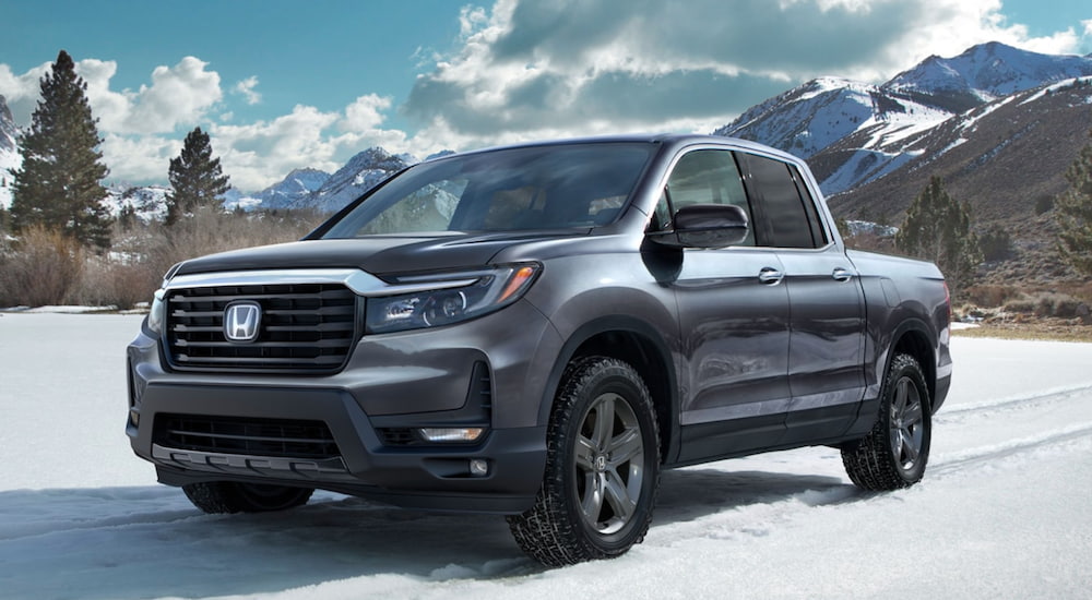 A grey 2021 Honda Ridgeline is parked in the snow after leaving a Certified Pre-Owned Honda Dealer.