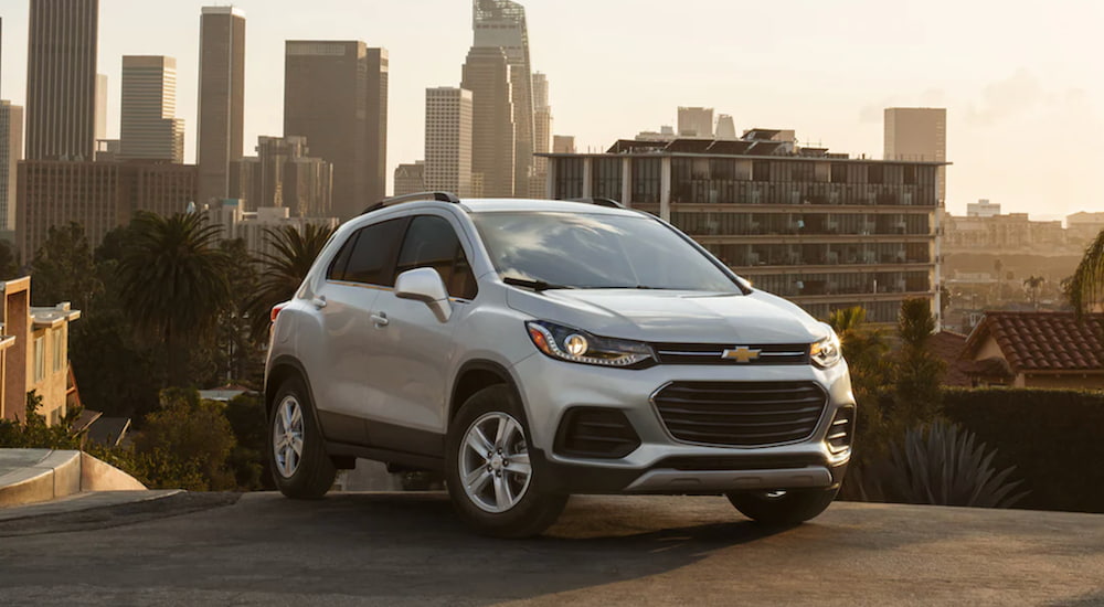 A white 2021 Chevy Trax is parked in a city at sunset.