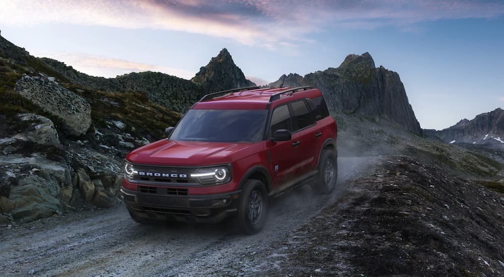 A red 2021 Ford Bronco Sport drives on a dirt road in the mountains.