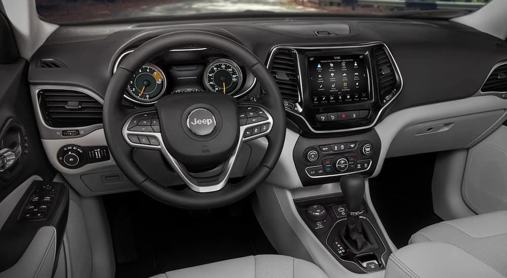 The interior of a 2021 Jeep Cherokee shows the steering wheel and infotainment screen.