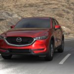 A red 2021 Mazda CX-5 is driving down an open road after leaving the Mazda CX-5 dealer.
