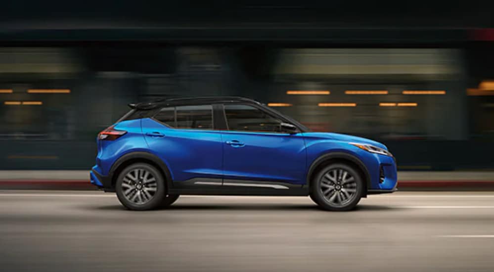 A blue 2022 Nissan Kicks is shown from the side driving through a city.