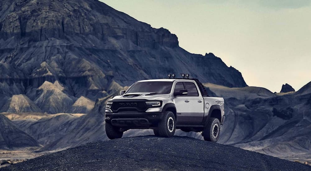 A silver 2021 Ram 1500 TRX is parked on dark dirt while off-roading.