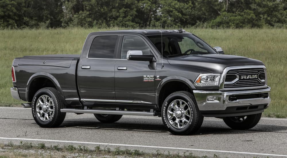 A grey 2016 Ram 2500 is shown from the side driving down an open road with forest behind it. 