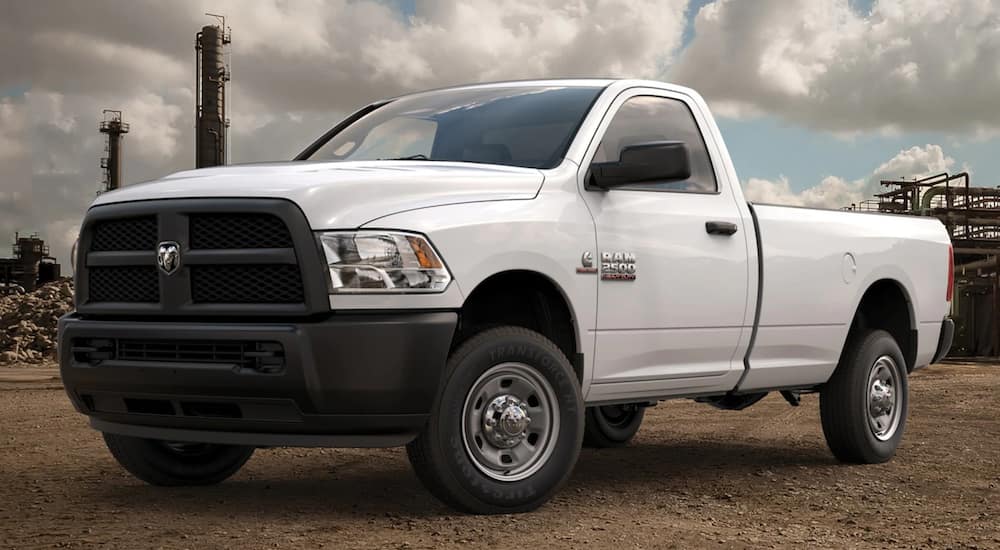 A white 2016 Ram 2500 is parked on dirt in front of a construction site.