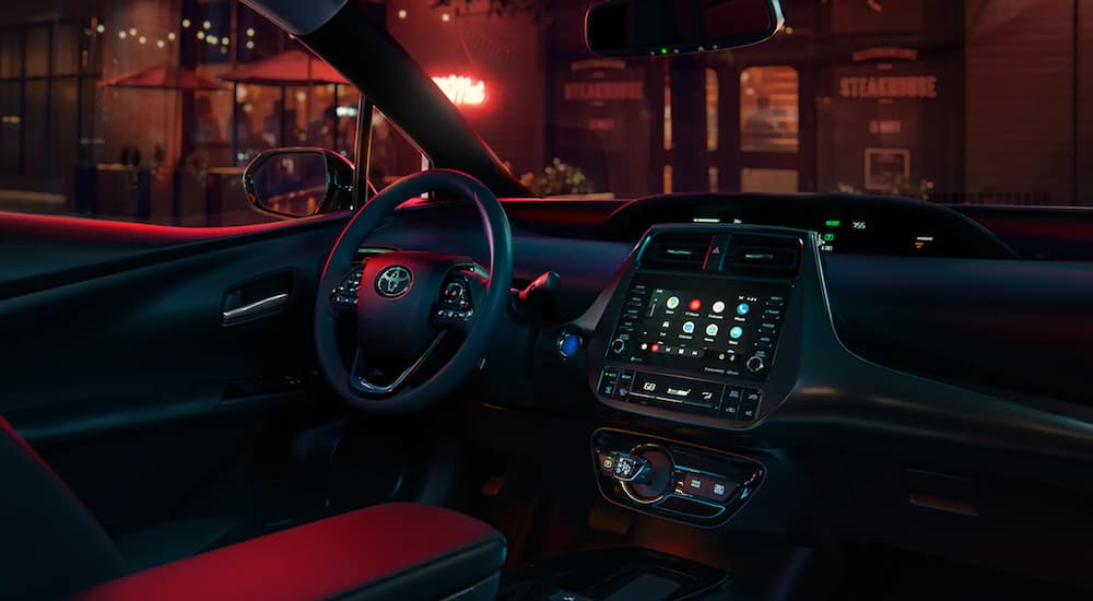 The interior of a 2021 Toyota Prius shows the steering wheel and infotainment screen.