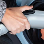 A hand is holding an electric car charger.