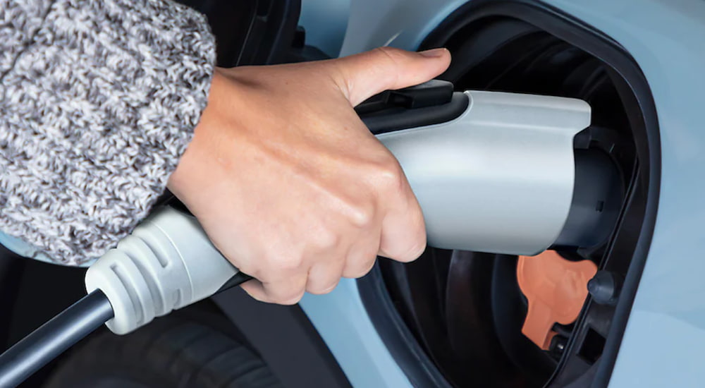 A hand is holding an electric car charger.