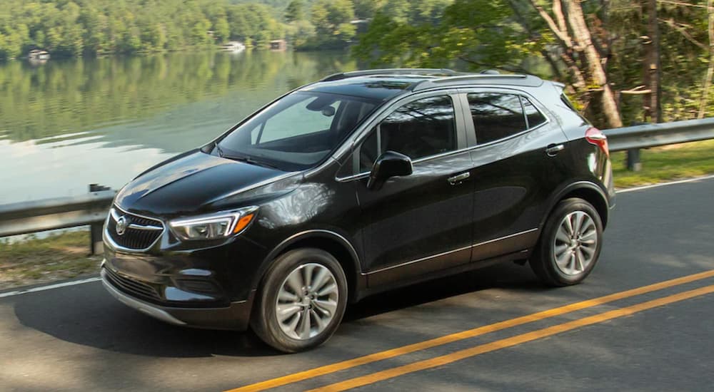 A black 2020 Buick Encore is shown from the side driving past a pond.