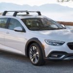 A white 2021 Buick Regal GS is parked on the side of a road in front of mountains after leaving a used Buick dealer.