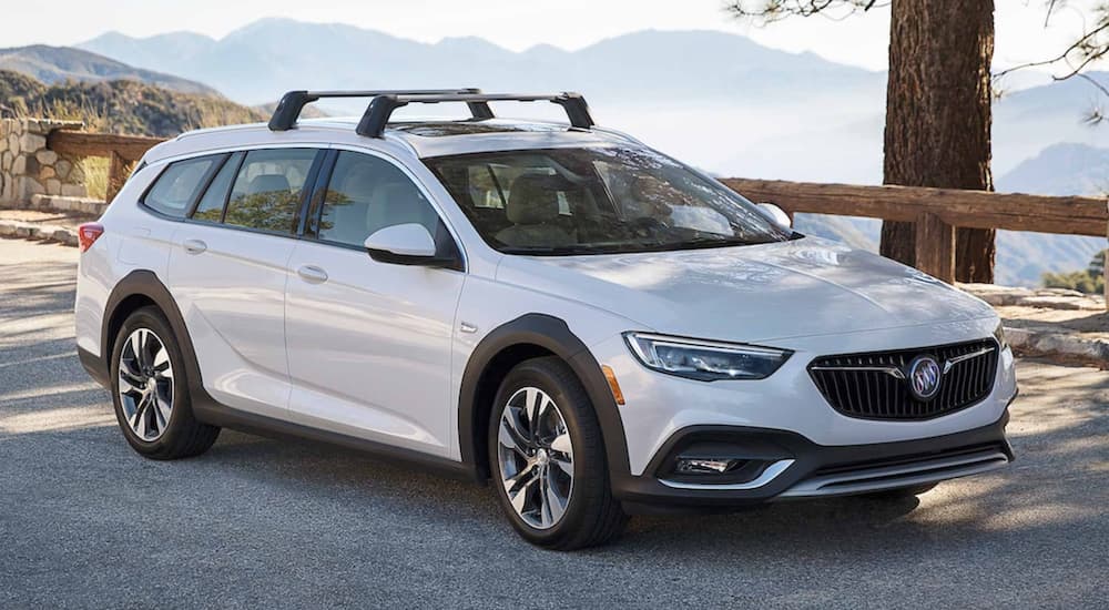 A white 2021 Buick Regal GS is parked on the side of a road in front of mountains after leaving a used Buick dealer.