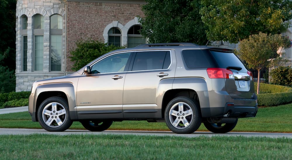 A gold 2013 GMC Terrain SLE is parked in the driveway of an estate.