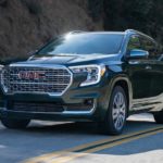 A black 2022 GMC Terrain Denali is driving down a two way road after leaving a used GMC Terrain dealer