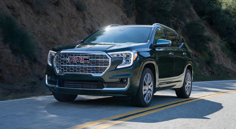 A black 2022 GMC Terrain Denali is driving down a two way road after leaving a used GMC Terrain dealer